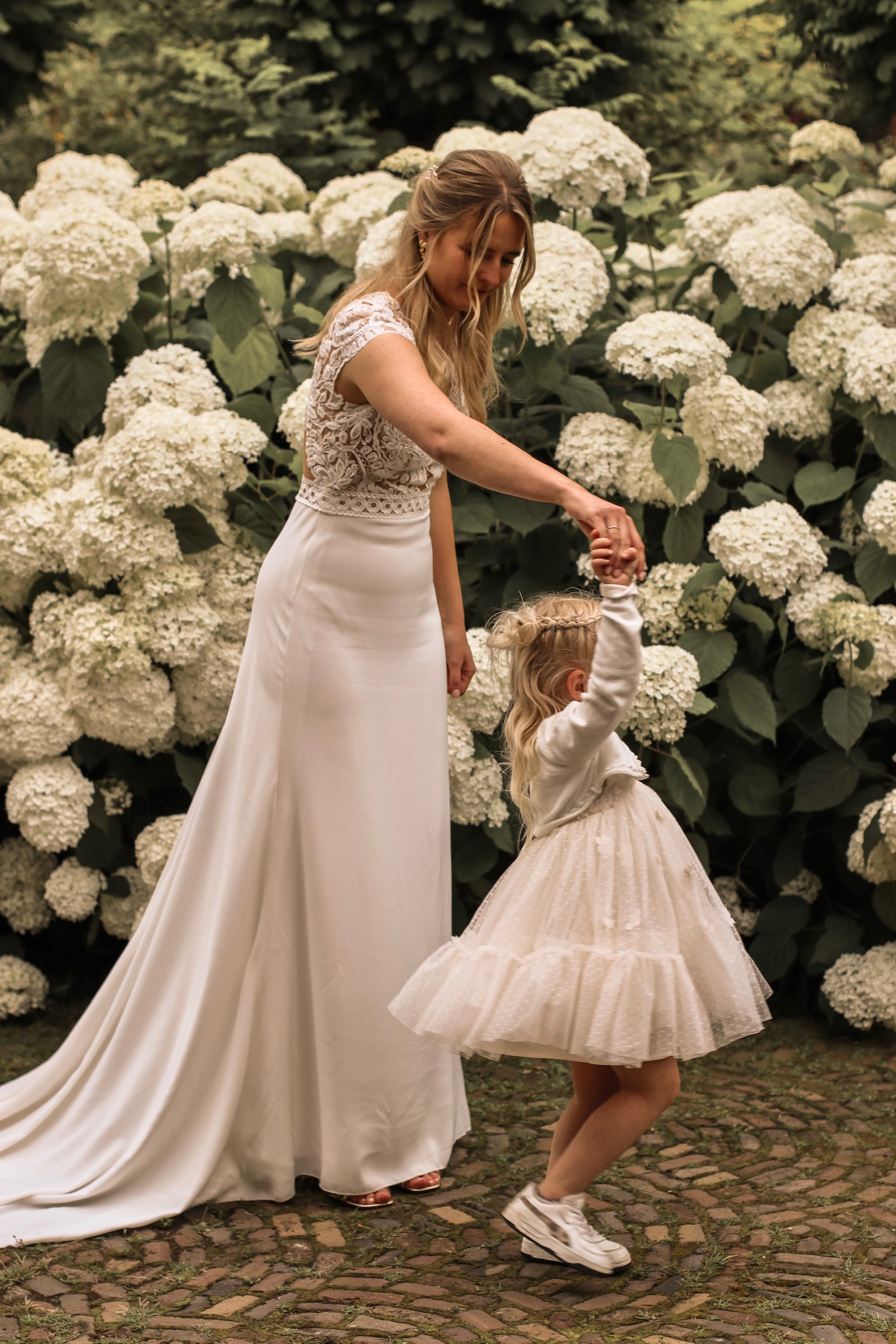 Bruiloft fotografie Haaksbergen - bruid met bruidsmeisje tussen hortensia's door Kim Scharenborg Fotografie