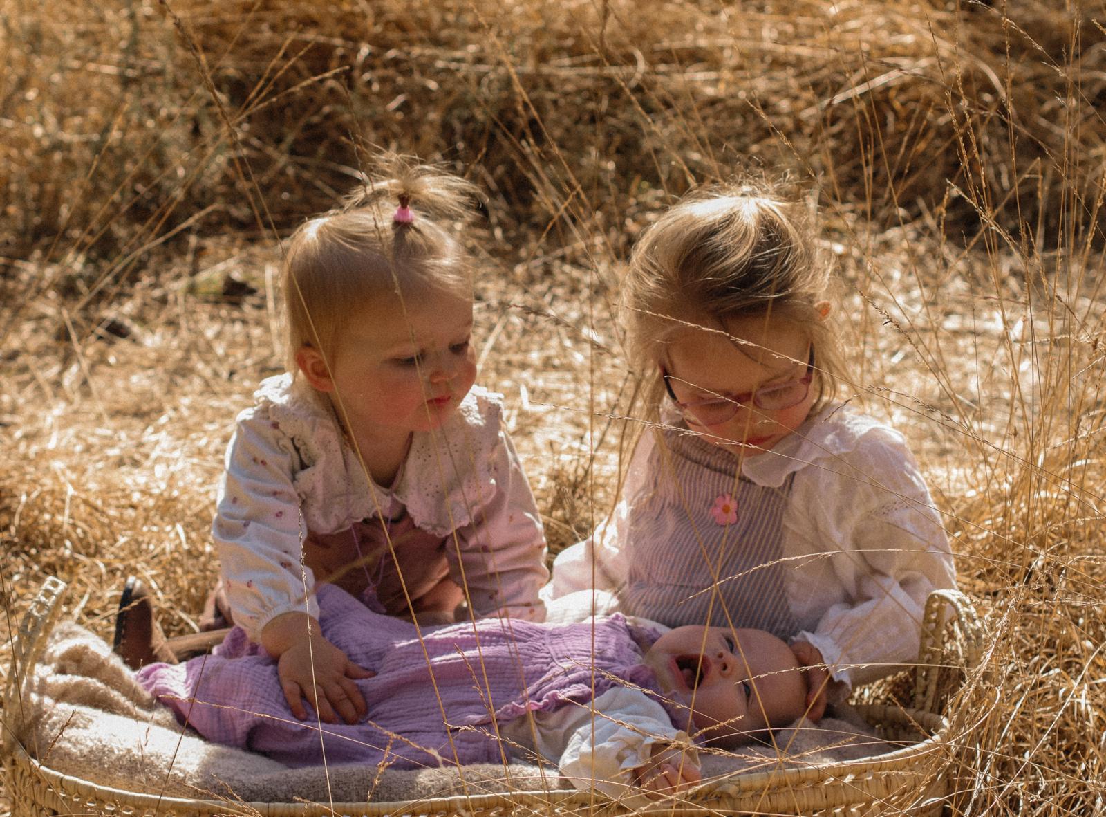 Familie fotografie Haaksbergen - twee meisjes in rieten mand in grasveld door Kim Scharenborg Fotografie