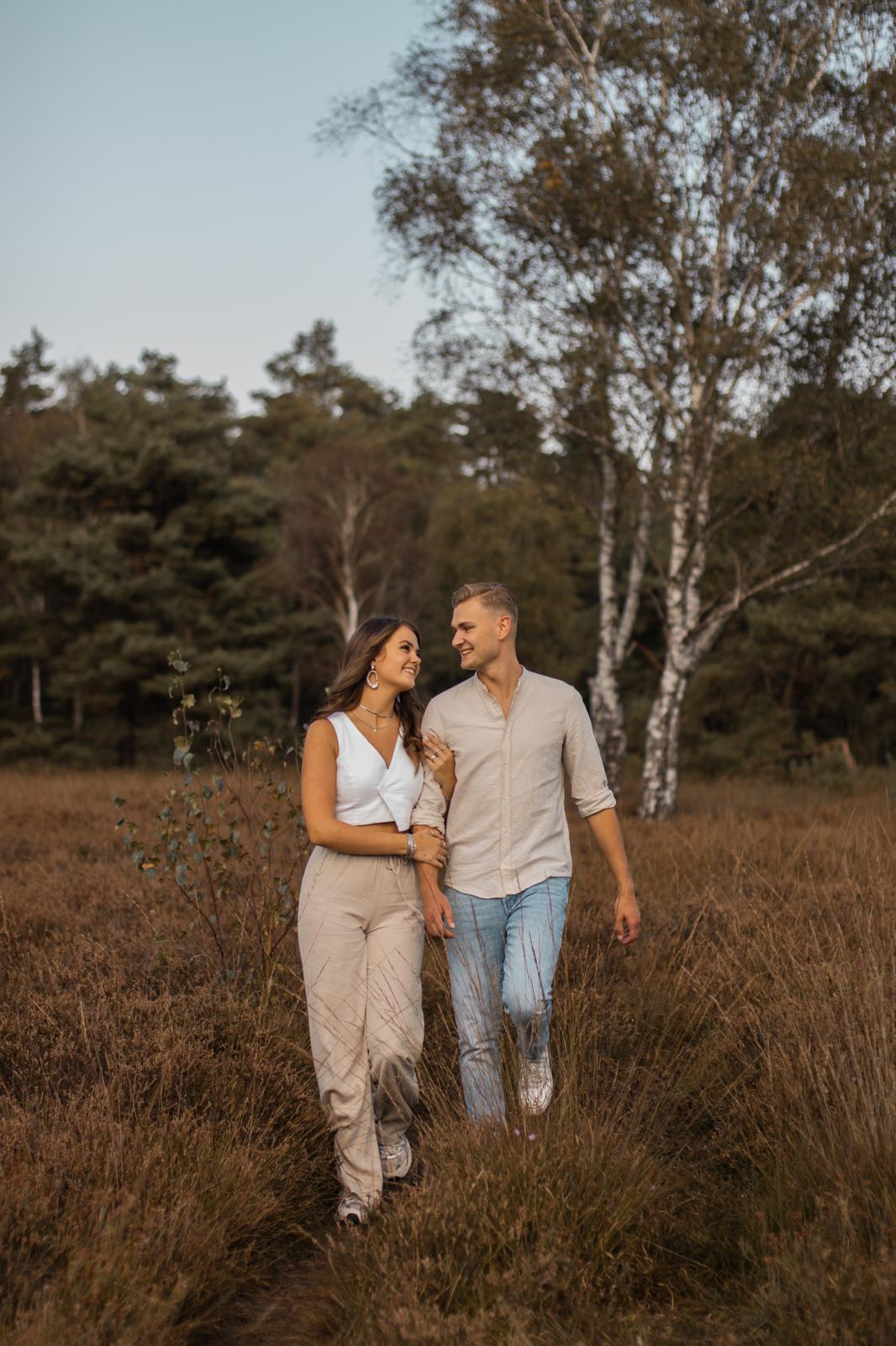 Koppel fotografie Haaksbergen - jong stel wandelt door veld door Kim Scharenborg Fotografie