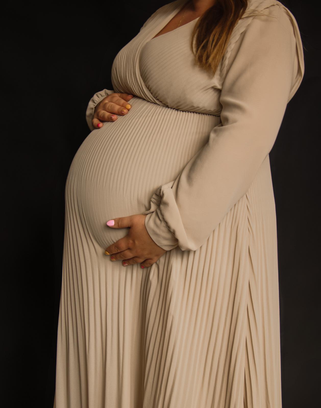 Zwangerschap fotografie Haaksbergen - vrouw in crèmekleurige jurk op zwarte achtergrond door Kim Scharenborg Fotografie